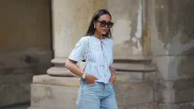 HAMBURG, GERMANY - MAY 7: Laura Noltemeyer is seen wearing a light indigo blue wide leg jeans from Agolde, a cotton puff sleeve blouse with ties in the front in white with blue stripes from Sézane, black oversized cat-eye acetate sunglasses from Celine, Arco handbag in white intrecciato leather from Bottega Veneta, big golden drop-shaped earrings, a small Lady-Datejust watch in gold-silver from Rolex, a golden LOVE bracelet from Cartier, stacked golden rings from Cartier on May 7, 2025 in Hamburg, Germany. (Photo by Moritz Scholz/Getty Images)