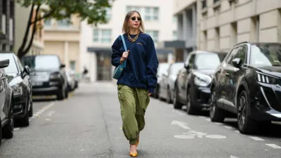 PARIS, FRANCE - NOVEMBER 09: Emy Venturini wears black Rayban sunglasses, a dark blue Supreme sweater, a gold Margiela necklace, a light blue leather Liase bag, khaki wide-leg pants, orange leather Roger Vivier high heels, during a street style fashion photo session, on November 09, 2024 in Paris, France. (Photo by Edward Berthelot/Getty Images)