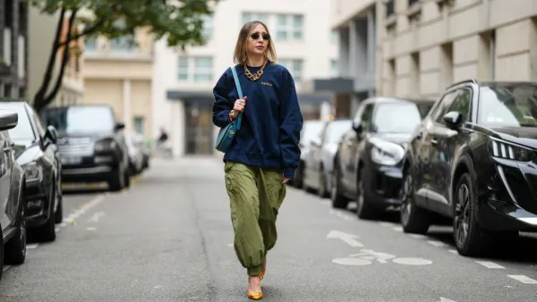 PARIS, FRANCE - NOVEMBER 09: Emy Venturini wears black Rayban sunglasses, a dark blue Supreme sweater, a gold Margiela necklace, a light blue leather Liase bag, khaki wide-leg pants, orange leather Roger Vivier high heels, during a street style fashion photo session, on November 09, 2024 in Paris, France. (Photo by Edward Berthelot/Getty Images)
