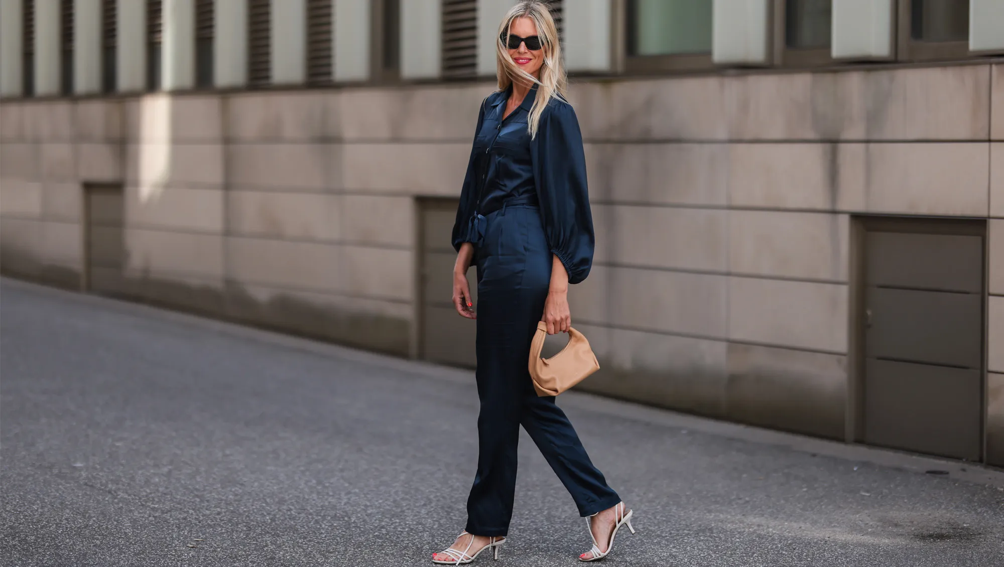 Vanessa Gieser seen wearing a black sunglasses from Celine, a dark bluse silk jumpsuit from SoSue, white leather heels from H&M and a beige leather Khaite bag on June 09, 2022 in Hamburg, Germany.