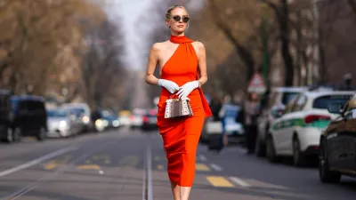 MILAN, ITALY - FEBRUARY 21: Leonie Hanne wears sunglasses, a red gathered sleeveless dress, a white gloves, a brown and white leather Fendi bag, outside Fendi, during the Milan Fashion Week - Womenswear Fall/Winter 2024-2025 on February 21, 2024 in Milan, Italy. (Photo by Edward Berthelot/Getty Images)