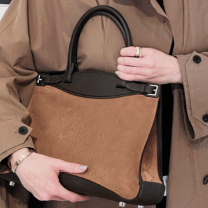 new hermes bridon bach in brown suede carried by a woman in a trenchcoat.