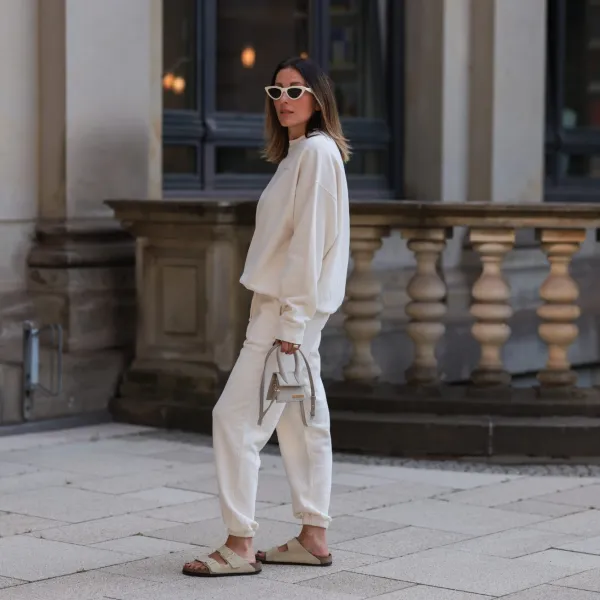 HAMBURG, GERMANY - AUGUST 16: Elise Seitz seen wearing white sunglasses from Celine, a creme white SohoStudios sweater, a creme white SohoStudios jogger pants, creme white linen Jacquemus Chiquito bag and beige suede Birkenstock Arizona sandals, on August 16, 2022 in Hamburg, Germany. (Photo by Jeremy Moeller/Getty Images)