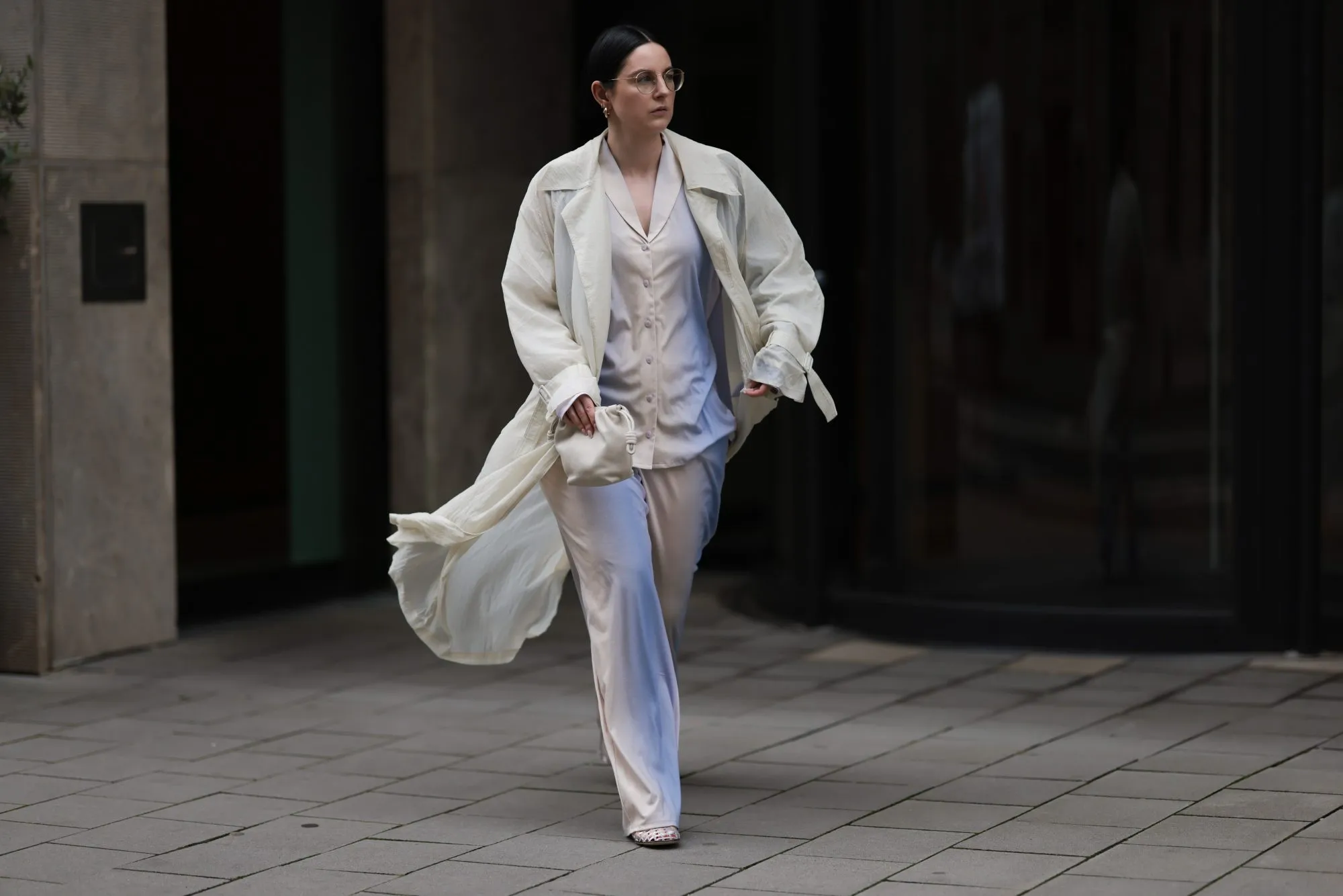 COLOGNE, GERMANY - AUGUST 23: Maria Barteczko seen wearing Ray-Ban gold round retro glasses, Hanro colorful ombré pyjama cotton set, The Frankie Shop cream white transparent lightweight trench coat, LOEWE cream white Flamenco small bag and The Row transparent jelly Mara flat shoes, on August 23, 2024 in Cologne, Germany. (Photo by Jeremy Moeller/Getty Images)