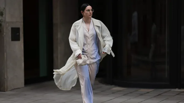 COLOGNE, GERMANY - AUGUST 23: Maria Barteczko seen wearing Ray-Ban gold round retro glasses, Hanro colorful ombré pyjama cotton set, The Frankie Shop cream white transparent lightweight trench coat, LOEWE cream white Flamenco small bag and The Row transparent jelly Mara flat shoes, on August 23, 2024 in Cologne, Germany. (Photo by Jeremy Moeller/Getty Images)