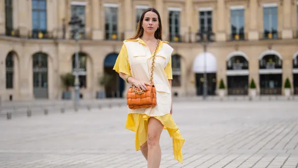 PARIS, FRANCE - MAY 07: Maria Rosaria Rizzo @lacoquetteitalienne wears a pale pastel yellow and beige shirt / flowing dress from Victoria/Tomas, a brown leather Bottega Veneta bag, sneakers from Nike Air Jordan with orange printed houndstooth patterns, on May 07, 2021 in Paris, France. (Photo by Edward Berthelot/Getty Images)