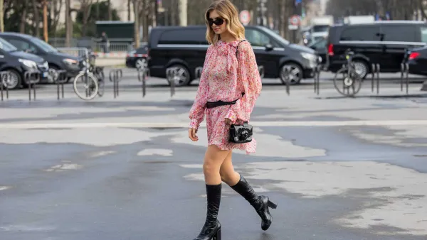 PARIS, FRANCE - MARCH 11: Xenia Adonts wears red white dress with belt, black bag, knee high boots outside Chanel during the Womenswear Fall/Winter 2025/2026 as part of Paris Fashion Week on March 11, 2025 in Paris, France. (Photo by Christian Vierig/Getty Images)