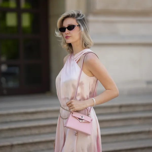 FRANKFURT AM MAIN, GERMANY - MAY 12: Mandy Bork is seen wearing black sunglasses with elliptical black Gucci embellished cat-eye glasses, a pink long dress from Peek&Cloppenburg Limited edition, a Hermès Mini Kelly in Rose Sakura with a silverfish metal detail as the button, Hermès ring and in rosegold, a bracelet by Chaîne d'Ancre Enchaînée Hermès as well as earrings, a Cartier love bracelet in silver, a tennis bracelet in silver/gold by Leo mathild, an Aloe jewelry initial bracelet on May 12, 2025 in Frankfurt am Main, Germany. (Photo by Moritz Scholz/Getty Images)