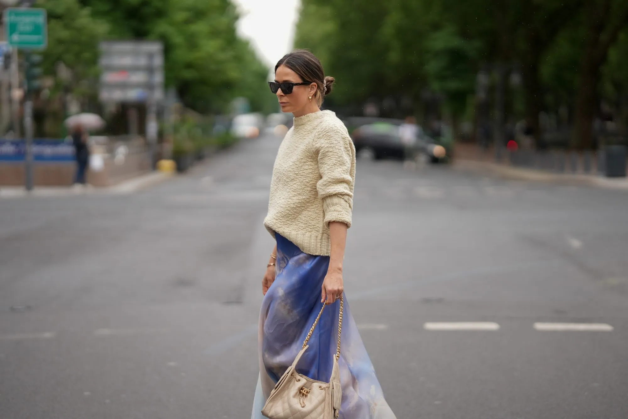 DUSSELDORF, GERMANY - MAY 27: Patricia Wirschke is seen wearing a blue printed silk-organza maxi skirt from Zimmermann, a cream white wool knit sweater with straight fit and round neckline from Jil Sander, brown cat-eye sunglasses with tortoiseshell finish from Celine, a beige small calfskin Chanel 25 hobo handbag with golden hardware and chain and logo details from Chanel, yellow golden Serpenti Viper hoop earrings with snake-like design from Bvlgari, a golden Juste un Clou bracelet from Cartier, a yellow golden Serpenti Viper bracelet with snake-like design from Bvlgari, a yellow golden Love bracelet from Cartier, a silver diamond ring on May 27, 2025 in Dusseldorf, Germany. (Photo by Moritz Scholz/Getty Images)
