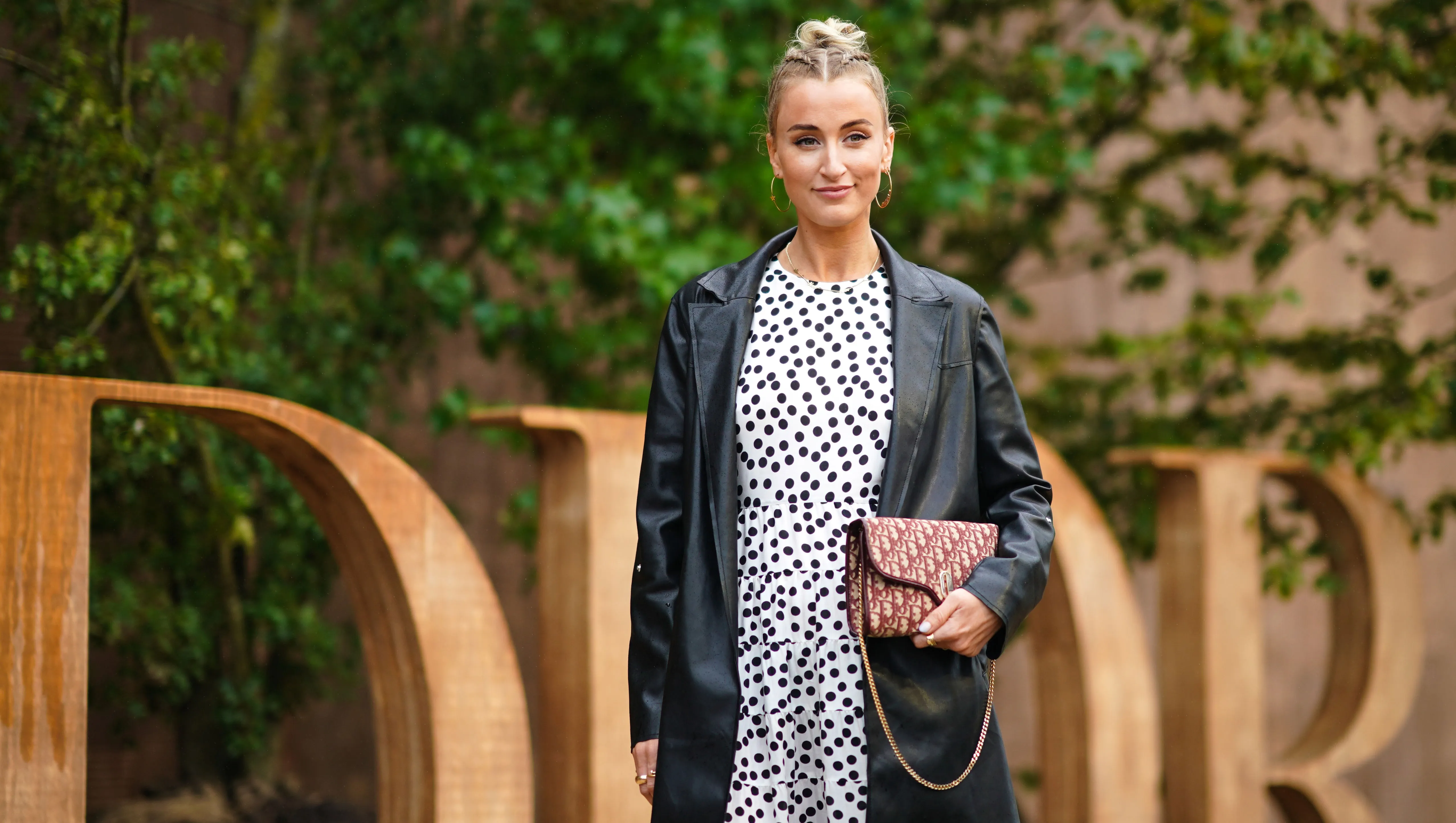 PARIS, FRANCE - SEPTEMBER 24: Noor de Groot wears large earrings, a black leather jacket, a white dress with printed polka dots, a Dior monogram logo bag wears, outside Dior, during Paris Fashion Week - Womenswear Spring Summer 2020, on September 24, 2019 in Paris, France. (Photo by Edward Berthelot/Getty Images)