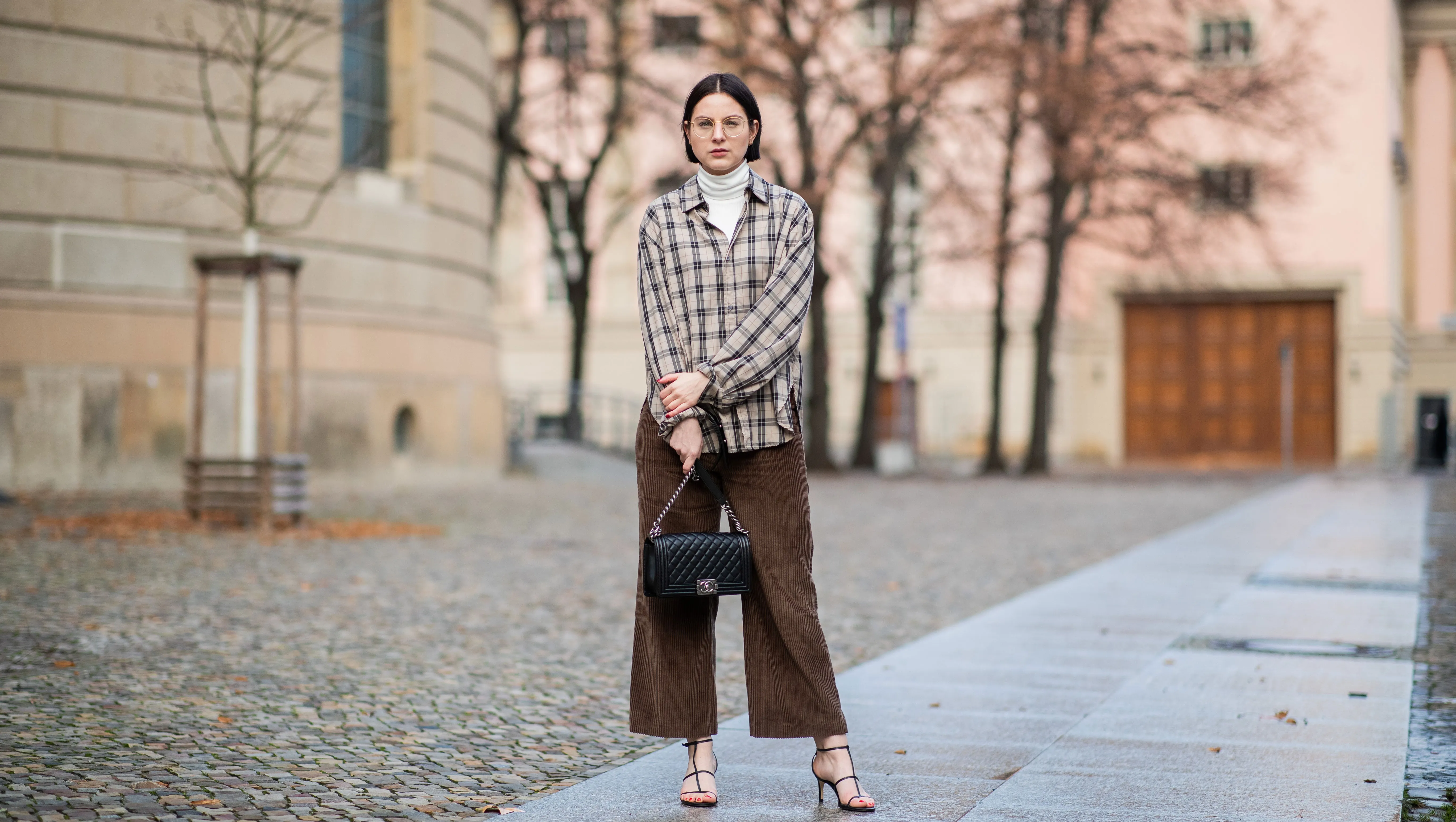 BERLIN, GERMANY - JANUARY 15: Maria Barteczko is seen wearing white turleneck COS, brown checked shirt Zara, brown corduroy pants Zara, black leather strap sandals Zara, black bag Chanel boy, gold round retro glasses Ray Ban during the Berlin Fashion Week Autumn/Winter 2019 on January 15, 2019 in Berlin, Germany. (Photo by Christian Vierig/Getty Images)