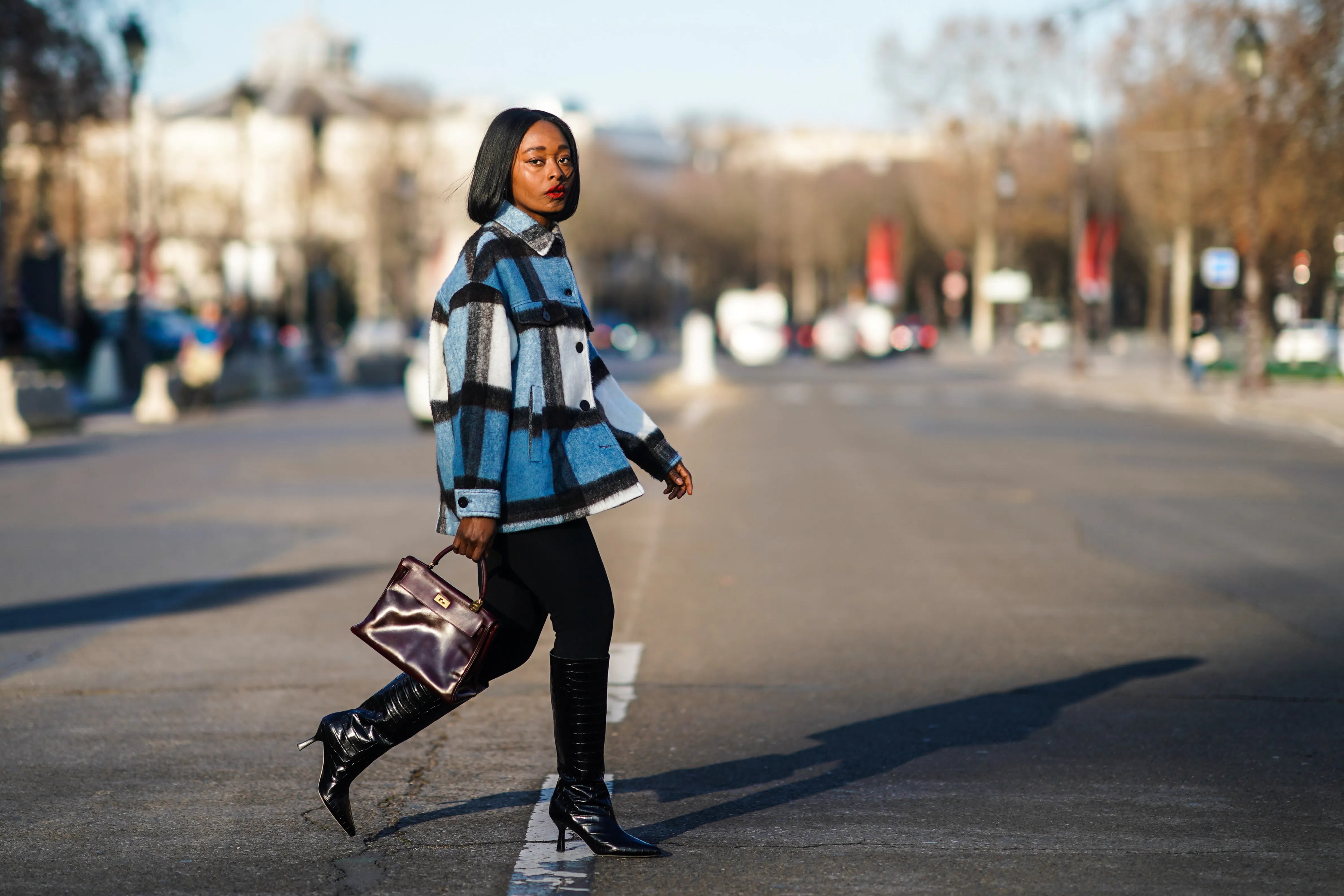 PARIS, FRANCE - JANUARY 09: Carrole Sagba aka "Linaose" wears a blue and white checked wool jacket from Zara, a purple / burgundy leather Hermes Birkin bag, black leggings/pants from Acne Studios, black pointy high heeled knee-high leather boots with printed crocodile patterns from Dear Frances, on January 09, 2021 in Paris, France. (Photo by Edward Berthelot/Getty Images)