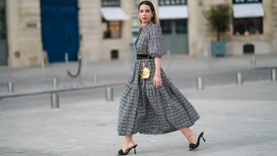 Maria Rosaria Rizzo @lacoquetteitalienne wears earrings, a grey gathered checked dress with puff sleeves from Parosh, a golden bracelet, a golden mini bag from Duren Japan, black leather sandals shoes from LPA, golden jewelry from & Other Stories, on March 03, 2021 in Paris, France.