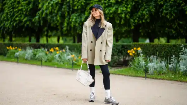 PARIS, FRANCE - MAY 27: Xenia Adonts wears a black cap from Museum of Peace and Quiet, a black ribbed turtleneck pullover, a beige long oversized jacket from Attire The Studio, black leggings from Nike, a white matte leather Bottega Veneta handbag, white socks, gray sneakers from New Balance, gold pink rings, on May 27, 2021 in Paris, France. (Photo by Edward Berthelot/Getty Images)