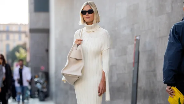 Linda Tol outside Max Mara fashion show wearing a knitted white dress, oversized white bag and sunglasses during the Milan Fashion Week - Spring / Summer 2022 on September 22, 2022 in Milan, Italy.