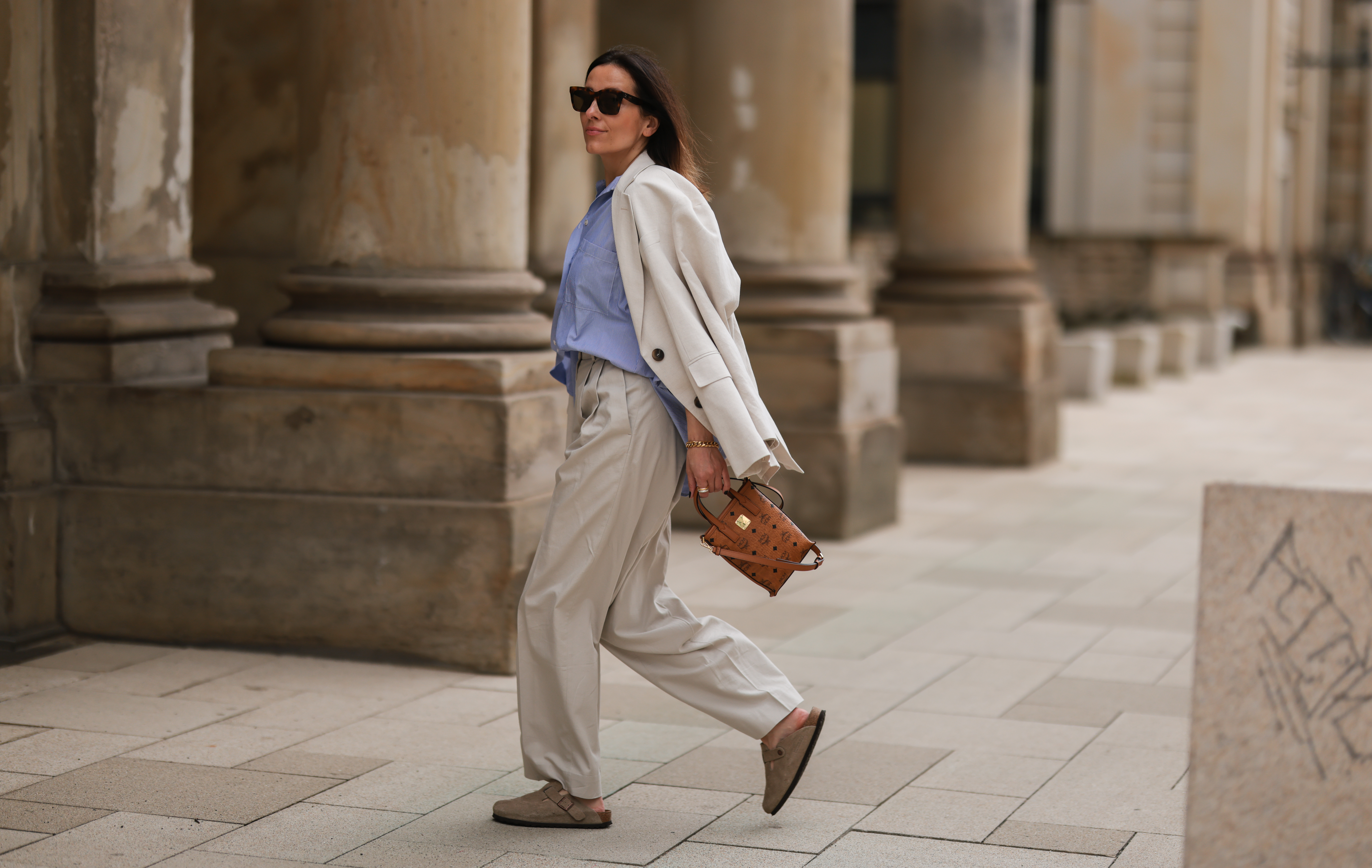Elise Seitz seen wearing a brown Celine sunglasses, a blue/white striped shirt blouse from Soho Studios, a creme wide leg pants from Cos, a creme oversize blazer from Soho Studios, beige wild leather Birkenstock sandals and a brown MCM logo bag on June 09, 2022 in Hamburg, Germany.