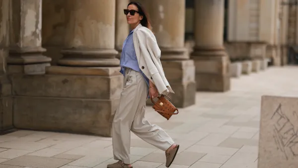 Elise Seitz seen wearing a brown Celine sunglasses, a blue/white striped shirt blouse from Soho Studios, a creme wide leg pants from Cos, a creme oversize blazer from Soho Studios, beige wild leather Birkenstock sandals and a brown MCM logo bag on June 09, 2022 in Hamburg, Germany.