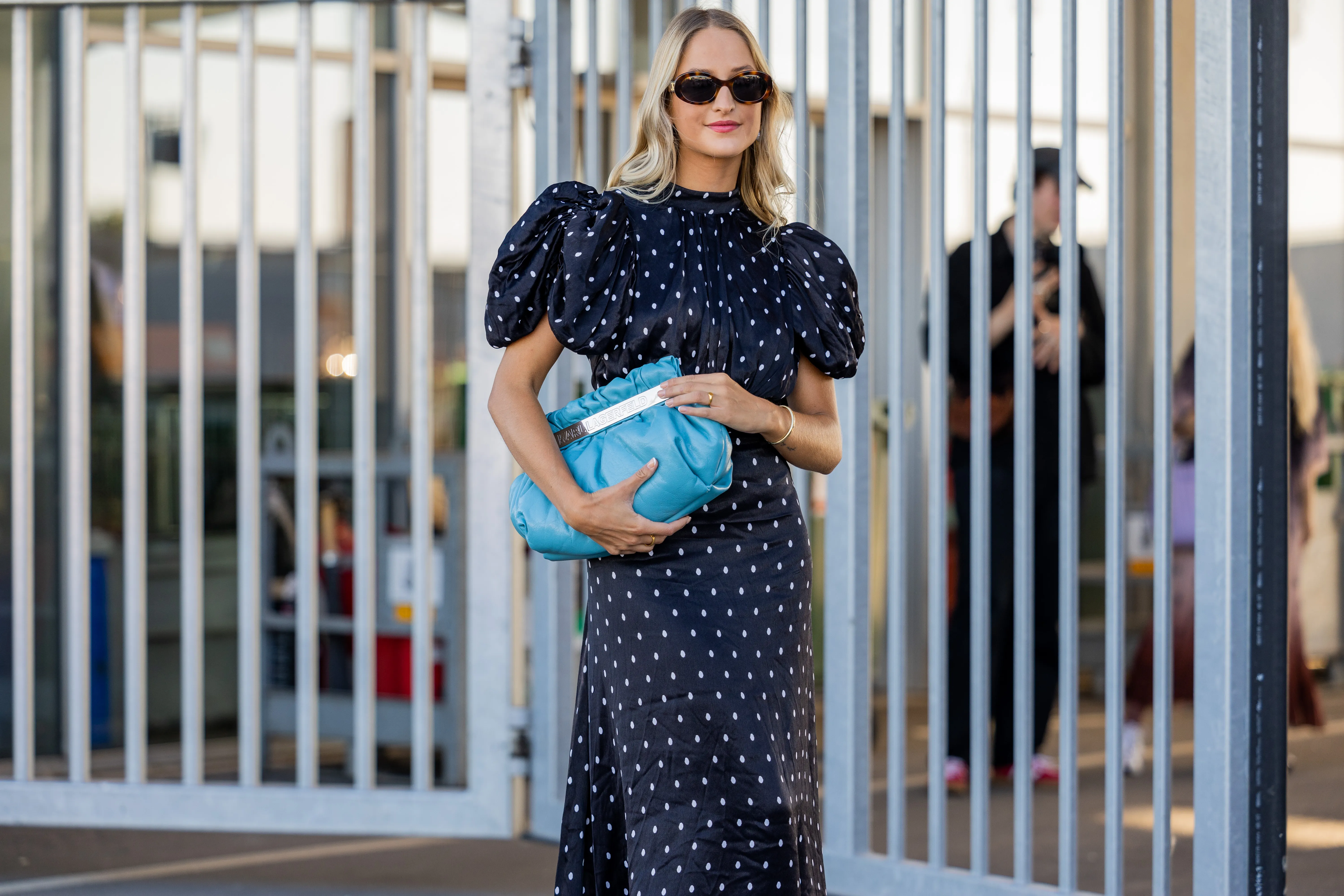 A guest seen wearing navy polka dot dress, blue bag, white sandals outside Munthe during Copenhagen Fashion Week Spring/Summer 2023 on August 11, 2022 in Copenhagen, Denmark.