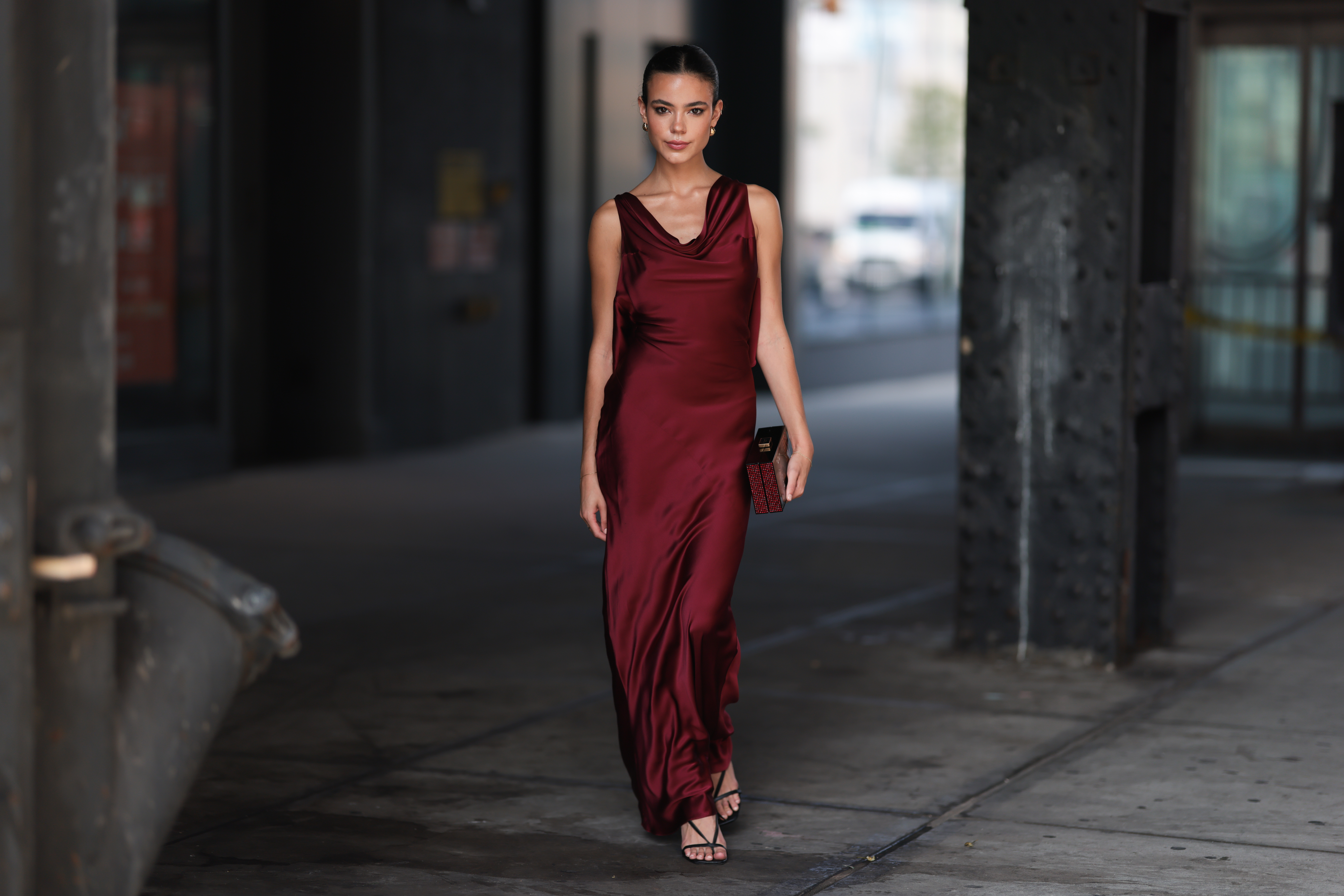 NEW YORK - SEPTEMBER 08: Ella Grace Mendelsohn is seen wearing golden earrings, a backless sleeveless wine-red satin maxi dress, a clutch from Kate Spade with red rhinestones and black strap heels outside before Kate Spade presentation on September 08, 2023 in New York City. (Photo by Jeremy Moeller/Getty Images)