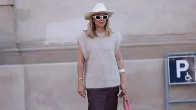 COPENHAGEN, DENMARK - AUGUST 07: Sonia Lyson is seen wearing a white cowboy hat, rectangular cat-eye sunglasses with bold white frame and wide temple from Miu Miu, golden hoop earrings, a golden chain necklace, a grey oversized wool tank top from The Garment, several golden bracelets, including the yellow-gold “Love“ bracelet from Cartier, a bold white bangle, several rings in gold and silver, a small rectangular quilted pink leather bag from Chanel, and an ankle-length dark purple leather skirt from Dorothee Schumacher before The Garment Show during day three of the Copenhagen Fashion Week (CPHFW) SS25 on August 07, 2024 in Copenhagen, Denmark. (Photo by Jeremy Moeller/Getty Images)