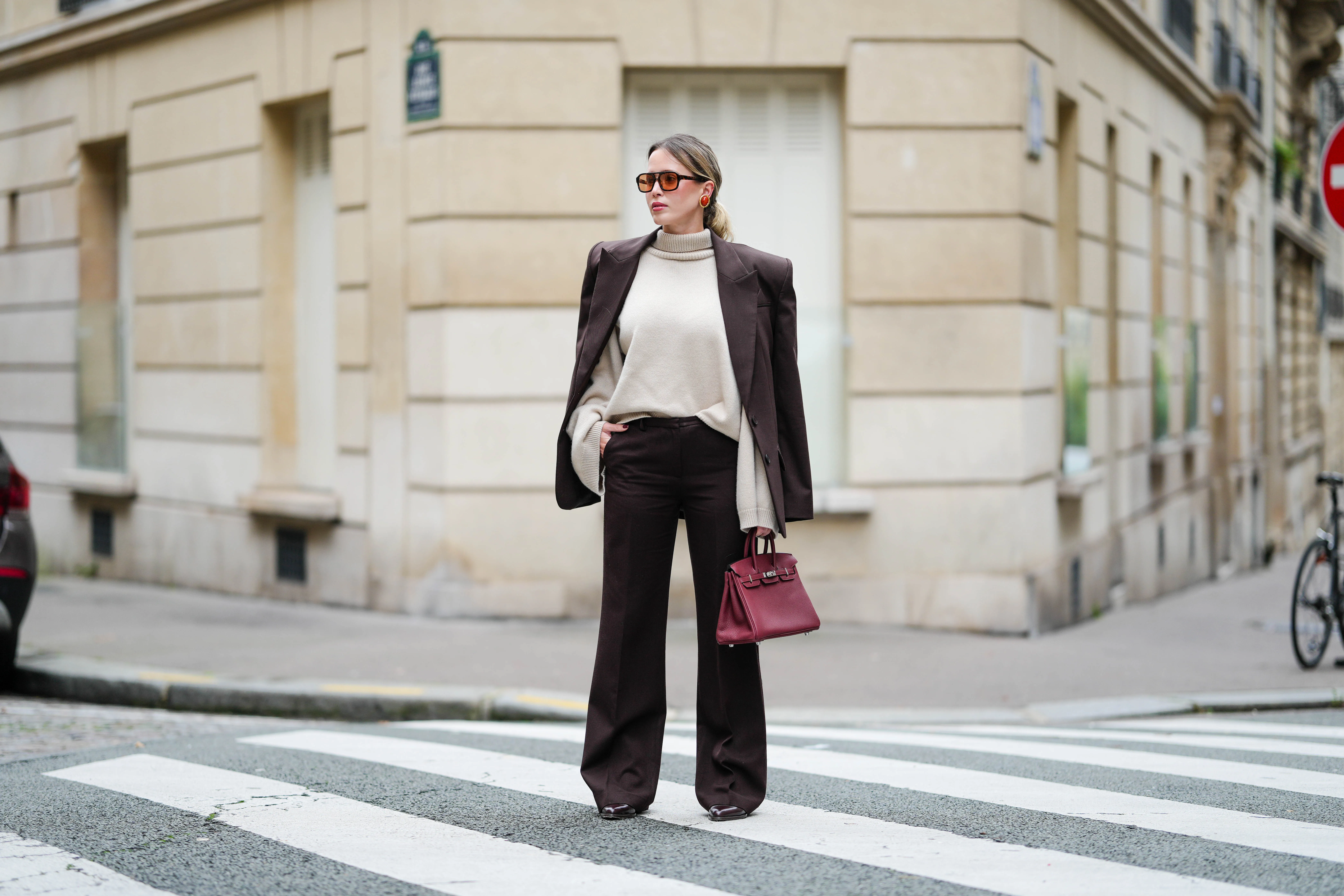 PARIS, FRANCE - OCTOBER 18: Virginie Conte wears black sunglasses, a beige turtleneck pullover, a dark brown Bazhane blazer jacket, dark brown Frankie shop pants, a burgundy leather Hermes bag, brown leather Jonak pointes shoes, during a street style fashion photo session, on October 18, 2024 in Paris, France. (Photo by Edward Berthelot/Getty Images)