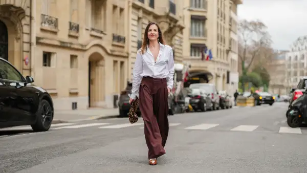 PARIS, FRANCE - DECEMBER 18: Alba Garavito Torre wears a white Figaret shirt, dark brown wide-leg Prassos pants, a brown Tras mi Bolsa bag with leopard patterns, tobacco heels slingback penny loafers from Miu Miu, during a street style fashion photo session, on December 18, 2024 in Paris, France. (Photo by Edward Berthelot/Getty Images)