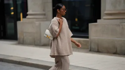 HAMBURG, GERMANY - SEPTEMBER 19: Cherifa Akili is seen wearing an oversized beige short-sleeve knit sweater with a soft texture from Byaylinkönig; a matching long knit skirt in a beige tone with subtle seaming at the hem from Byaylinkönig; red pointed-toe heels with a low cut from Prada; The Constance structured white leather shoulder bag with a gold clasp from Hermes; a gold spiral shaped bracelet from Elouise; two gold, metallic rings from Elouise, Wempe; lightly tinted sunglasses in a warm shade COS; her black hair is pulled back in a sleek bun on September 19, 2025 in Hamburg, Germany. (Photo by Moritz Scholz/Getty Images)