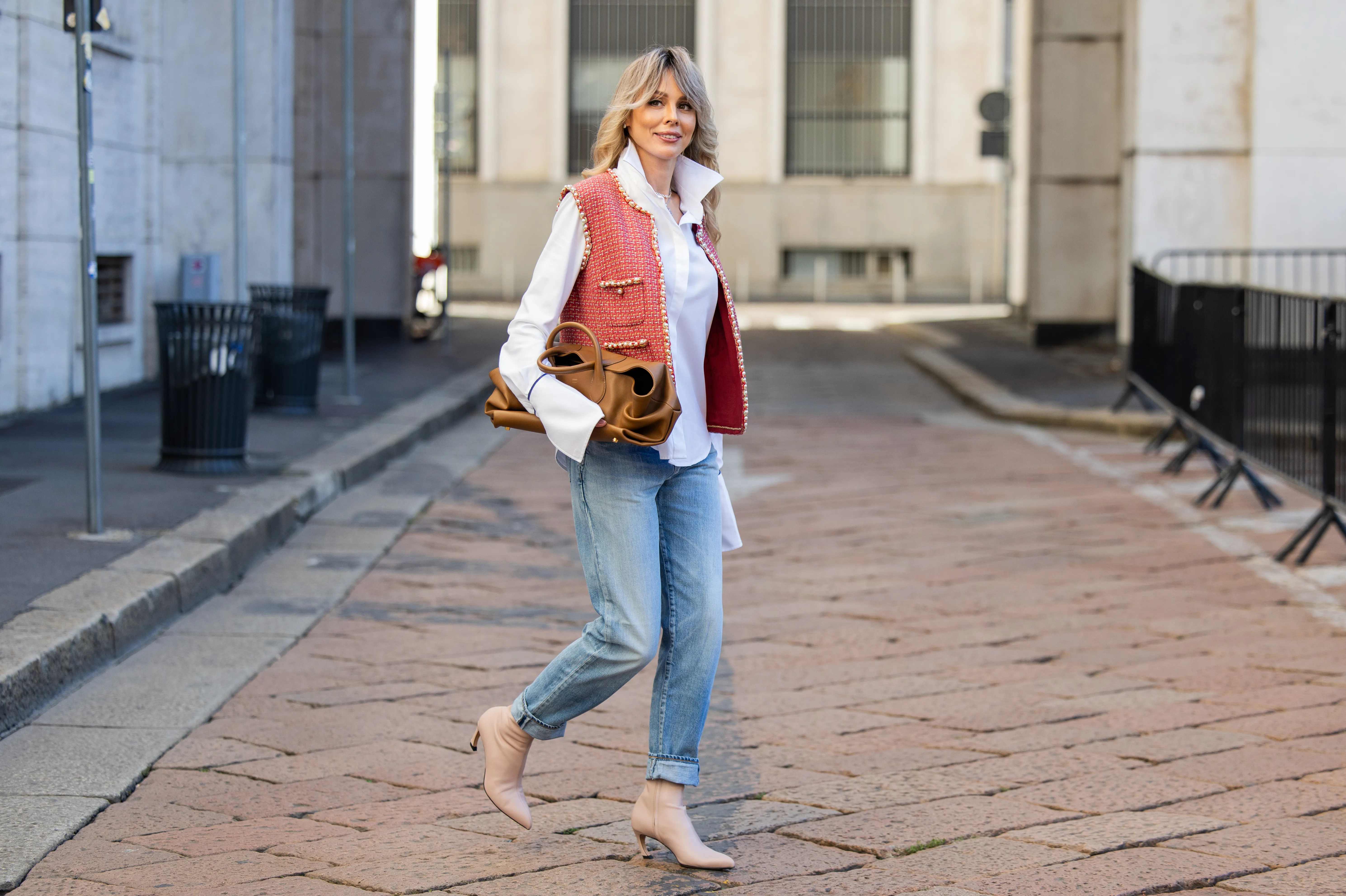 MILAN, ITALY - SEPTEMBER 28: Ekaterina Mamaeva wears white shirt Anna Quan, red vest Chanel, jeans Saint Laurent, rose ankle boots Acne Studios, brown bag Khaite during the Milan Fashion Week Womenswear Spring/Summer 2026 on September 28, 2025 in Milan, Italy. (Photo by Christian Vierig/Getty Images)