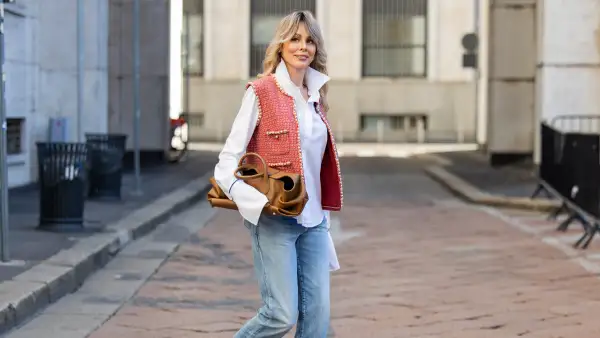 MILAN, ITALY - SEPTEMBER 28: Ekaterina Mamaeva wears white shirt Anna Quan, red vest Chanel, jeans Saint Laurent, rose ankle boots Acne Studios, brown bag Khaite during the Milan Fashion Week Womenswear Spring/Summer 2026 on September 28, 2025 in Milan, Italy. (Photo by Christian Vierig/Getty Images)
