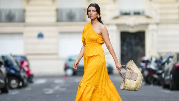 PARIS, FRANCE - AUGUST 12: Ketevan Giorgadze @katie.one wears a one shoulder cut out maxi dress in orange from Mango, oversized golden hoop earrings from Zara, flip flop heeled black sandals shoes from APC Paris, a Le Grand Panier beach straw bag by Jacquemus, on August 12, 2021 in Paris, France. (Photo by Edward Berthelot/Getty Images)
