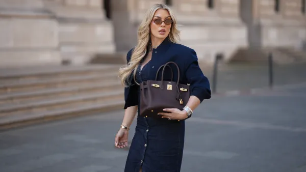 FRANKFURT AM MAIN, GERMANY - MAY 12: Paulina Kurka is seen wearing a navy blue cropped bomber jacket with big pockets from Zara, a denim midi dress with tailored waist and front button closure from Zara, light havana MU 04ZS sunglasses with round brown glasses and golden logo detail from Miu Miu, a chocolate brown Birkin 30 bag with golden details from Hermès, a silver triple wrap Farandole 120 fine link necklace with classic pendants from Hermès, silver hoop earrings, a medium sized silver Santos watch with square dial from Cartier, a silver Chaine d'ancre Enchainee chain bracelet from Hermès, a silver Chaine d'ancre Enchainee large model chain ring from Hermès, a custom-made diamond ring with square sapphire statement details, custom-made diamond engagement and wedding rings on May 12, 2025 in Frankfurt am Main, Germany. (Photo by Moritz Scholz/Getty Images)
