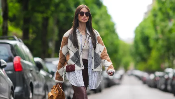PARIS, FRANCE - APRIL 27: Heart Evangelista wears sunglasses, a golden necklace, a gray brown and white wool cardigan with checked patterns, a white t-shirt from Saint-Laurent YSL, a belt, burgundy slit leather pants , a burgundy leather mini quilted Chanel bag, an orange / brown large Hermes bag, brown shoes, during a street style fashion photo session, on April 27, 2024 in Paris, France. (Photo by Edward Berthelot/Getty Images)