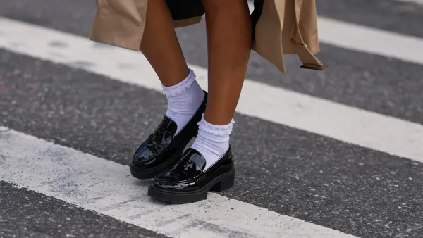 NEW YORK, NEW YORK - SEPTEMBER 15: A guest wears a beige trench coat, black patent varnished leather chunky lug-sole loafers shoes worn with white crew socks, outside Coach, during New York Fashion Week, on September 15, 2025 in New York, New York (Photo by Edward Berthelot/Getty Images)