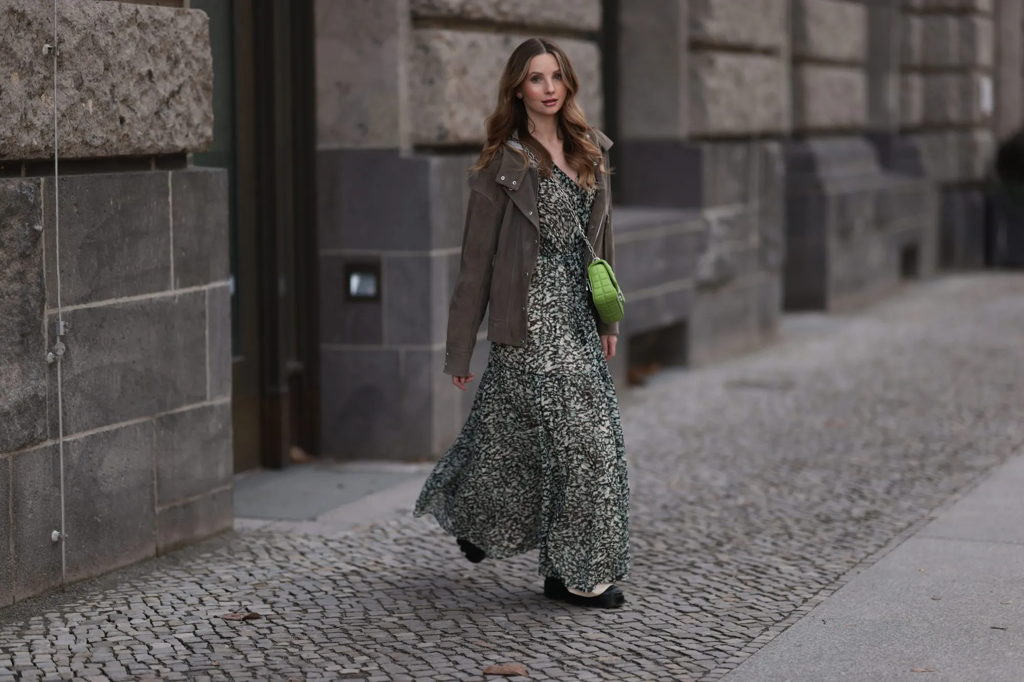 BERLIN, GERMANY - FEBRUARY 16: Anna Hiltrop seen wearing Boss green / beige / black print pattern pleated long dress, Boss brown suede leather jacket, Michael Kors green leather quilted crossbody bag and Gucci black leather laced boots, on February 16, 2024 in Berlin, Germany. (Photo by Jeremy Moeller/Getty Images)