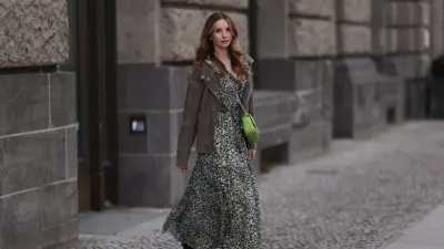 BERLIN, GERMANY - FEBRUARY 16: Anna Hiltrop seen wearing Boss green / beige / black print pattern pleated long dress, Boss brown suede leather jacket, Michael Kors green leather quilted crossbody bag and Gucci black leather laced boots, on February 16, 2024 in Berlin, Germany. (Photo by Jeremy Moeller/Getty Images)