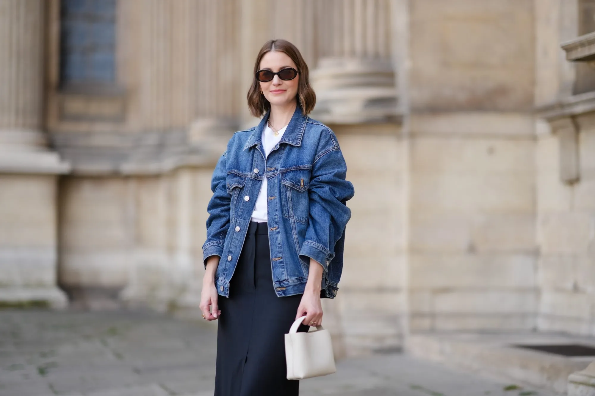 PARIS, FRANCE - MAY 25: Marissa Cox wears an Arket black skirt, an Arket white t-shirt, a blue oversize Agolde denim jacket, a white Arket leather bag, Jimmy Fairly x Reformation sunglasses, and Alighieri necklace, during a street style fashion photo session, on May 25, 2024 in Paris, France. (Photo by Edward Berthelot/Getty Images)