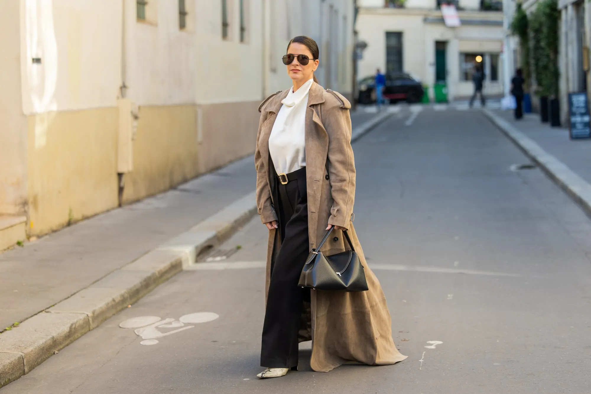 PARIS, FRANCE - SEPTEMBER 29: Gili Biegun wears extra long beige suede coat, snake leather boots, black leather Toteme T lock bag, black trousers and white Silk Turtle neck blouseduring the Womenswear Spring Summer 2026 as part of Paris Fashion Week on September 29, 2025 in Paris, France. (Photo by Christian Vierig/Getty Images)