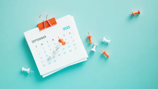 September 2025 calendar and thumbtacks on blue background. Horizontal composition. Reminder concept.