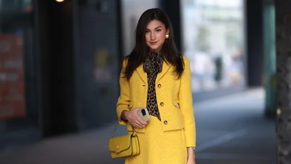 NEW YORK, NEW YORK - SEPTEMBER 08: A Fashion Week guest is seen wearing black sunglasses, golden earrings, a yellow matching two-piece from Kate Spade consisting of a jacket with golden buttons and a mini skirt, underneath a brown/black top with animal print and a bow, a silver/golden watch, a yellow leather bag from Kate Spade and pumps with ankle strap and animal print from Kate Spade outside before Kate Spade presentation on September 08, 2023 in New York City. (Photo by Jeremy Moeller/Getty Images)