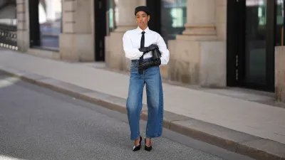 HAMBURG, GERMANY - AUGUST 17: Cherifa Akili is seen wearing a long-sleeved white button-down blouse from Closed, tucked into the jeans; a slim black necktie from Drykorn; high-waisted, wide-leg blue jeans in a mid-wash denim from Veronica Beard; black leather gloves on both hands covering the wrists and forearms from Zara; a black leather handbag with a golden top handle, carried in one hand from Elle Me; A small, fitted black pillbox-style hat; her hair is tucked into a slight bun; shiny-black pointed-toe stiletto pumps from 10TH FLOOR; narrow sunglasses with slightly angular edges and dark tinted lenses from Ysl on August 17, 2025 in Hamburg, Germany. (Photo by Moritz Scholz/Getty Images)