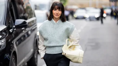 MILAN, ITALY - SEPTEMBER 20: Alexandra Pereira wears beige bag, black pants, green sleeveless pullunder, white button shirt outside Tods during the Milan Fashion Week Menswear Spring/Summer 2025 on September 20, 2024 in Milan, Italy. (Photo by Christian Vierig/Getty Images)