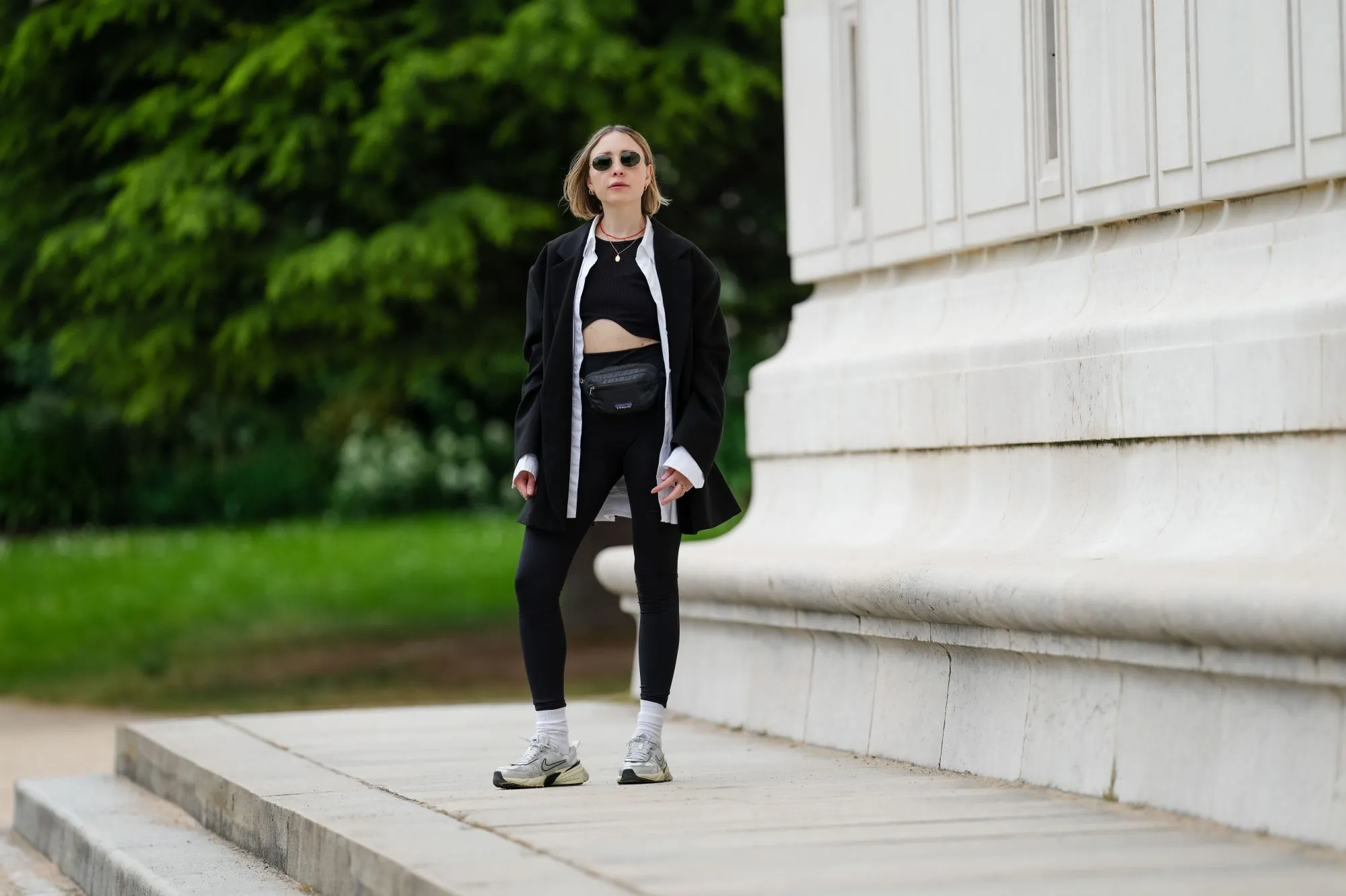 PARIS, FRANCE - MAY 12: Emy Venturini wears sunglasses from Ray Ban, a necklace, a white shirt from Louis Vuitton, a black Zara crop top, a black oversize blazer jacket from The Frankie Shop, black leggings from Intimissimi, white socks from Calzedonia, Nike sneakers shoes, a black leather belt bag / fanny pack from Patagonia, during a street style fashion photo session, on May 12, 2024 in Paris, France. (Photo by Edward Berthelot/Getty Images)