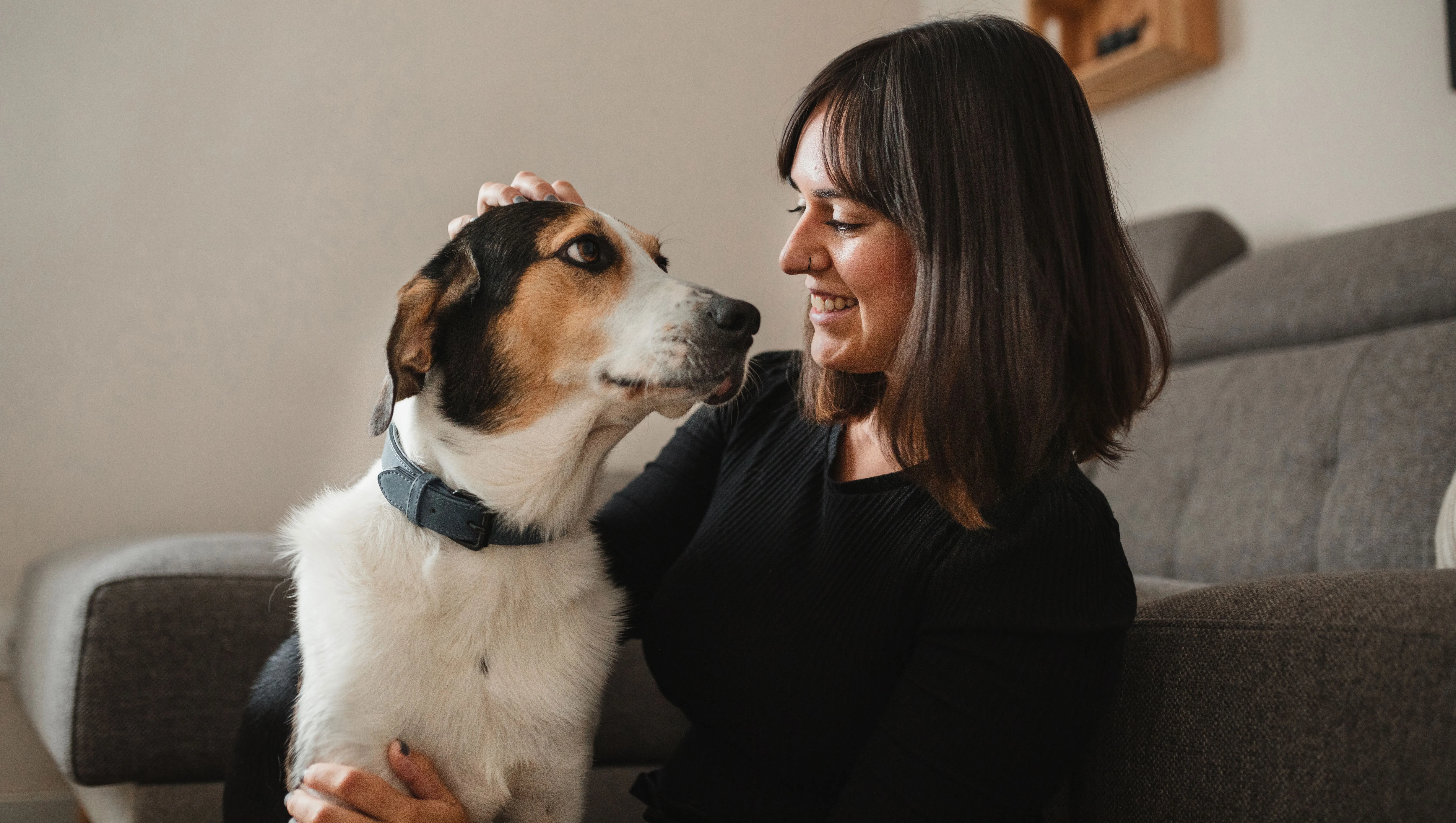front view of an adult woman with her dog at home hugging