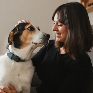 front view of an adult woman with her dog at home hugging