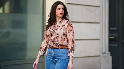 Sara Carnicella @lafillerebelle wears earrings from APM Monaco, a pink and purple floral print flowing shirt from Liu Jo, a brown leather belt from Mango, blue denim flared jeans from & Other Stories, on March 28, 2021 in Paris, France.