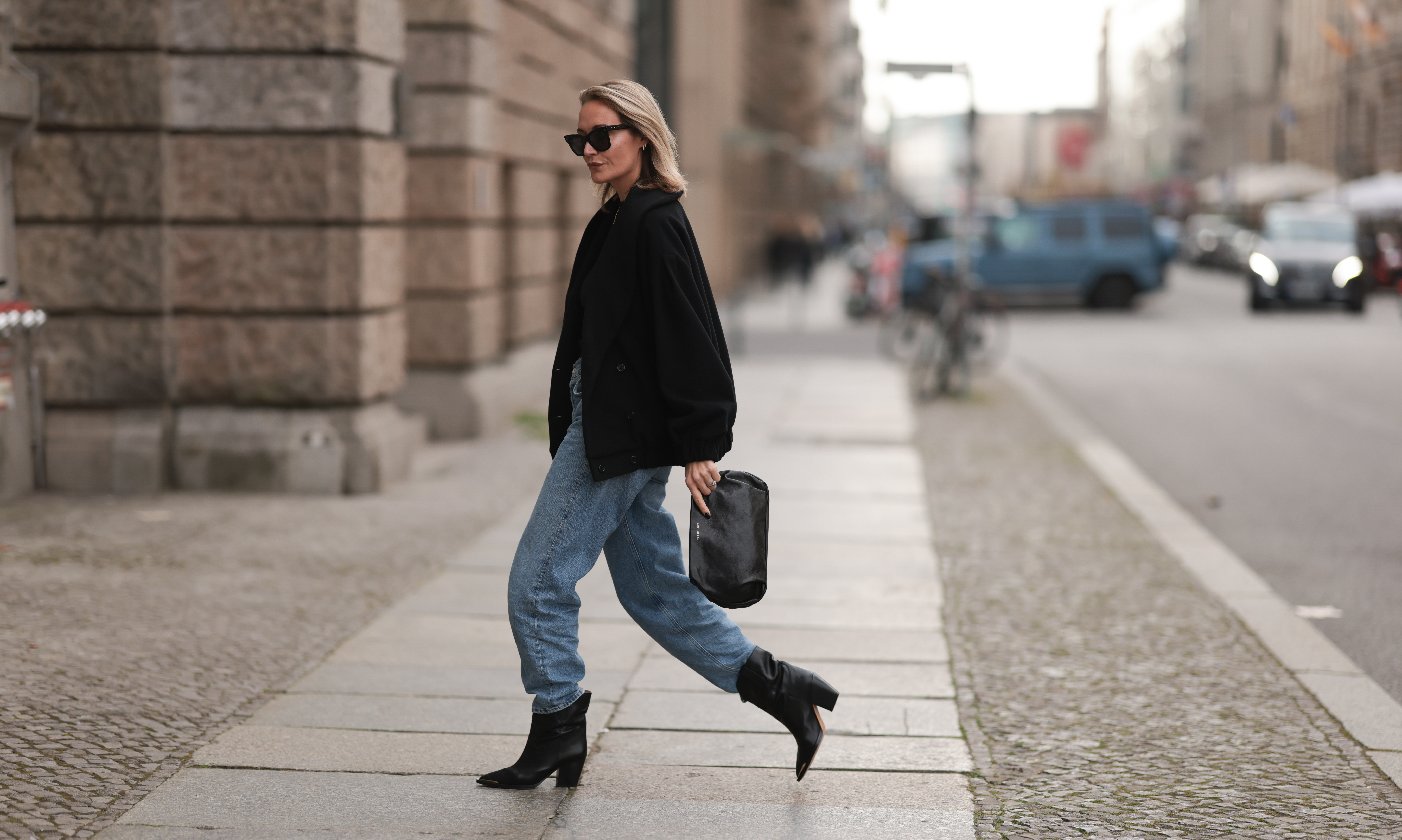 Lena Nussbaum is seen wearing black sunglasses from YES MY LOVE, black sweater, black jacket and black leather clutch bag from YES MY LOVE, blue denim Agolde pants and black YES MY LOVE leather boots, on October 13, 2022 in Berlin, Germany.