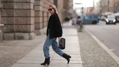 Lena Nussbaum is seen wearing black sunglasses from YES MY LOVE, black sweater, black jacket and black leather clutch bag from YES MY LOVE, blue denim Agolde pants and black YES MY LOVE leather boots, on October 13, 2022 in Berlin, Germany.