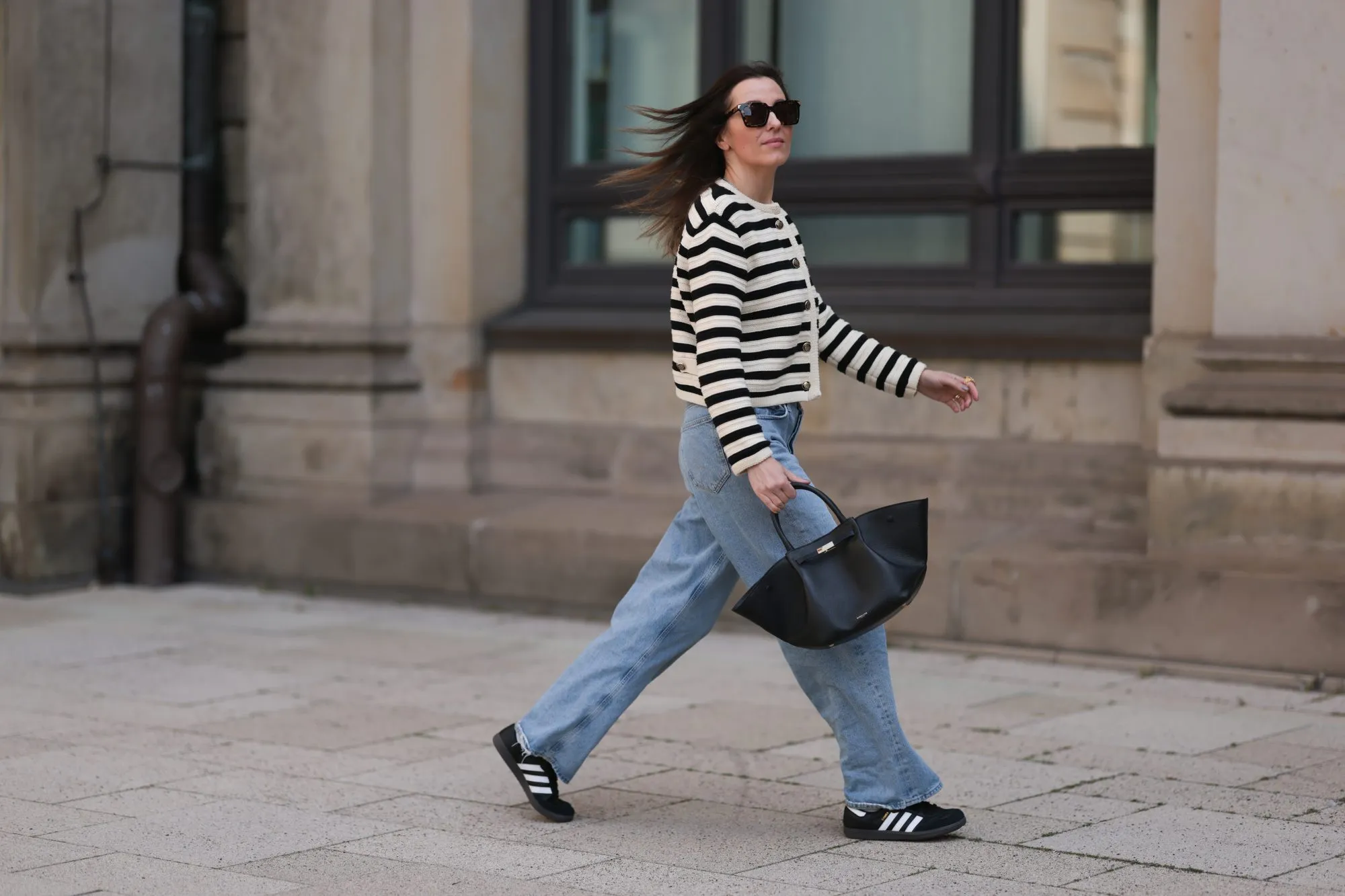 Elise Seitz seen wearing Bottega Veneta black shades, Celine black belt, Adidas black samba sneaker, Agolde blue jeans, Massimo Dutti striped black and white cardigan and Demellier black bag on May 09, 2023 in Hamburg, Germany.