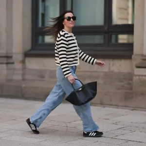 Elise Seitz seen wearing Bottega Veneta black shades, Celine black belt, Adidas black samba sneaker, Agolde blue jeans, Massimo Dutti striped black and white cardigan and Demellier black bag on May 09, 2023 in Hamburg, Germany.