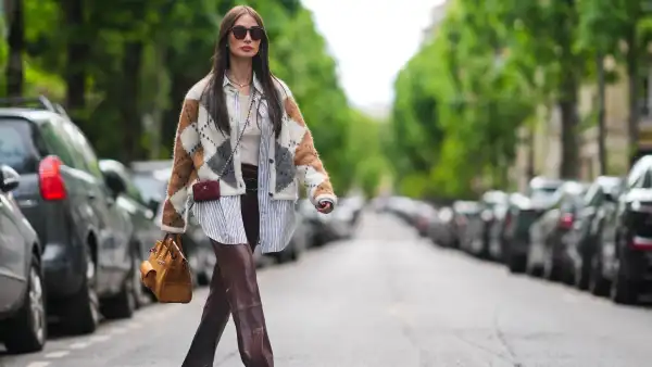 PARIS, FRANCE - APRIL 27: Heart Evangelista wears sunglasses, a golden necklace, a gray brown and white wool cardigan with checked patterns, a white t-shirt from Saint-Laurent YSL, a belt, burgundy slit leather pants , a burgundy leather mini quilted Chanel bag, an orange / brown large Hermes bag, brown shoes, during a street style fashion photo session, on April 27, 2024 in Paris, France. (Photo by Edward Berthelot/Getty Images)